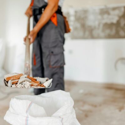 A close up of a young Caucasian man holding a shovel filled with construction residue.