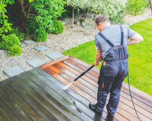 cleaning terrace with a power washer - high water pressure cleaner on wooden terrace surface